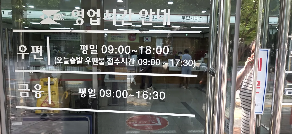 Glass-door hours notice showing postal counters open until 18:00 and financial counters closing at 16:30.