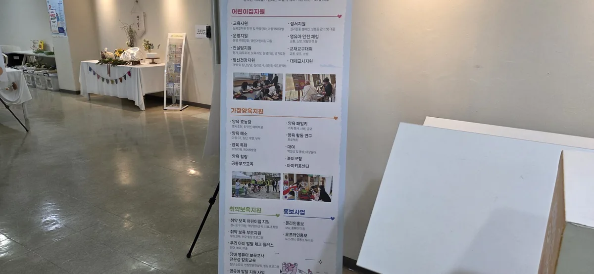 Standing program banner at the childcare support center listing its services, including rental of 백일상 and 돌상.
