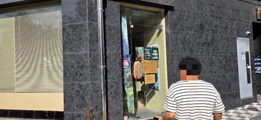 Entrance of Fullmoon, a Bongdam pet friendly no kids cafe, with a green NO KIDS ZONE sign posted on the glass door beside the dark stone facade.